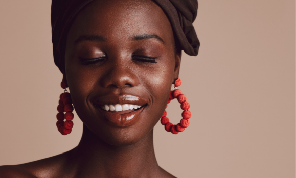 Woman smiling, eyes closed, round orange beaded earrings